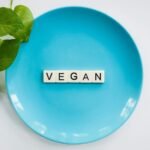 A blue plate with the word 'VEGAN' and a leafy plant, symbolizing a plant-based diet.